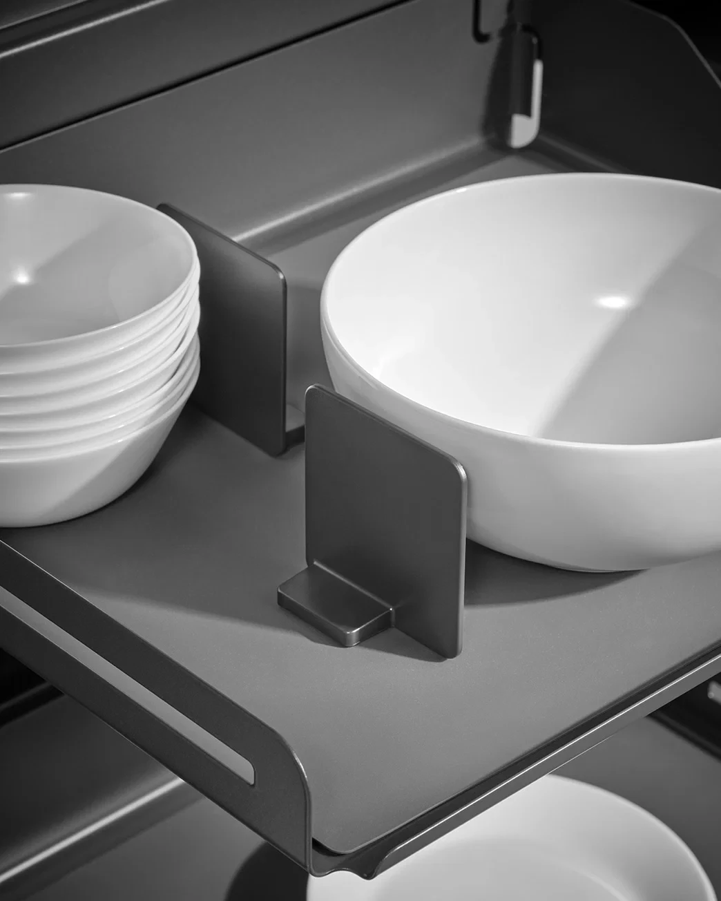 Close-up of a formed metal kitchen organizer with rounded edges and white ceramic bowls.