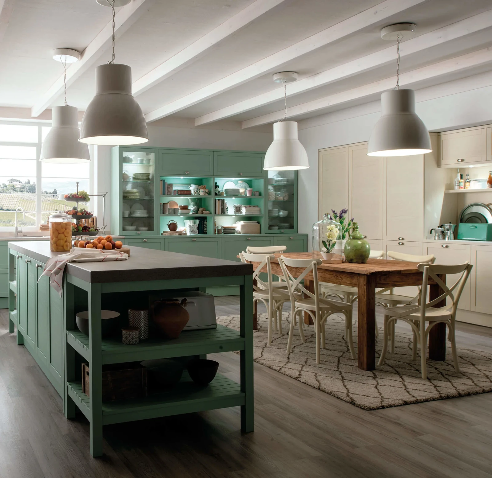 Light-filled kitchen with green cabinetry, a preparation island and a shared wooden dining table.